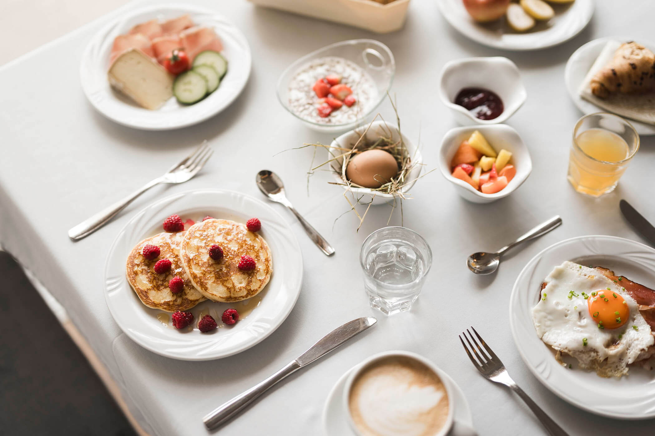 Pancakes mit Himbeeren und weitere Gerichte am Frühstückstisch