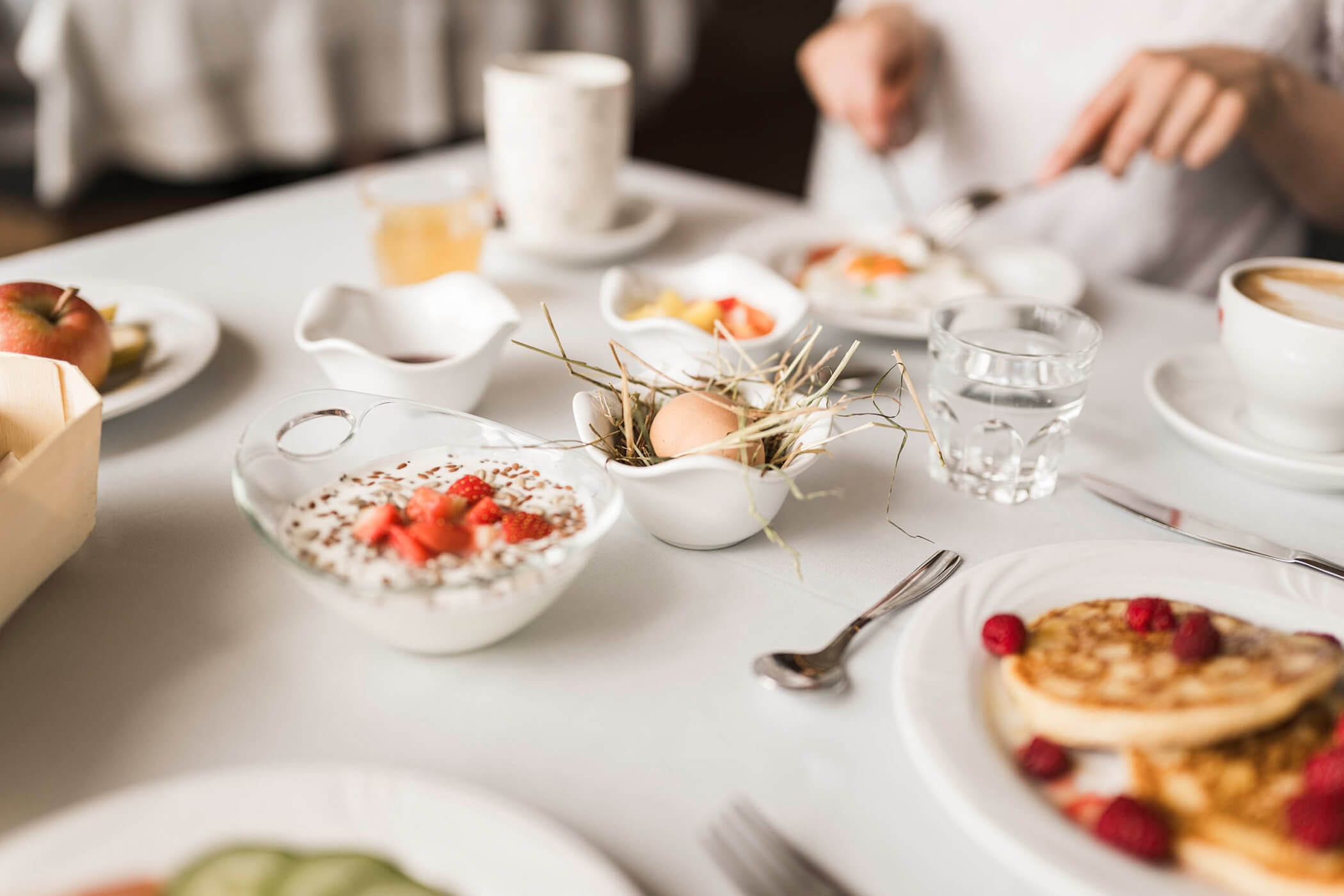 Frühstückstisch mit Joghurt, Eiern, Pancakes und Vieles mehr