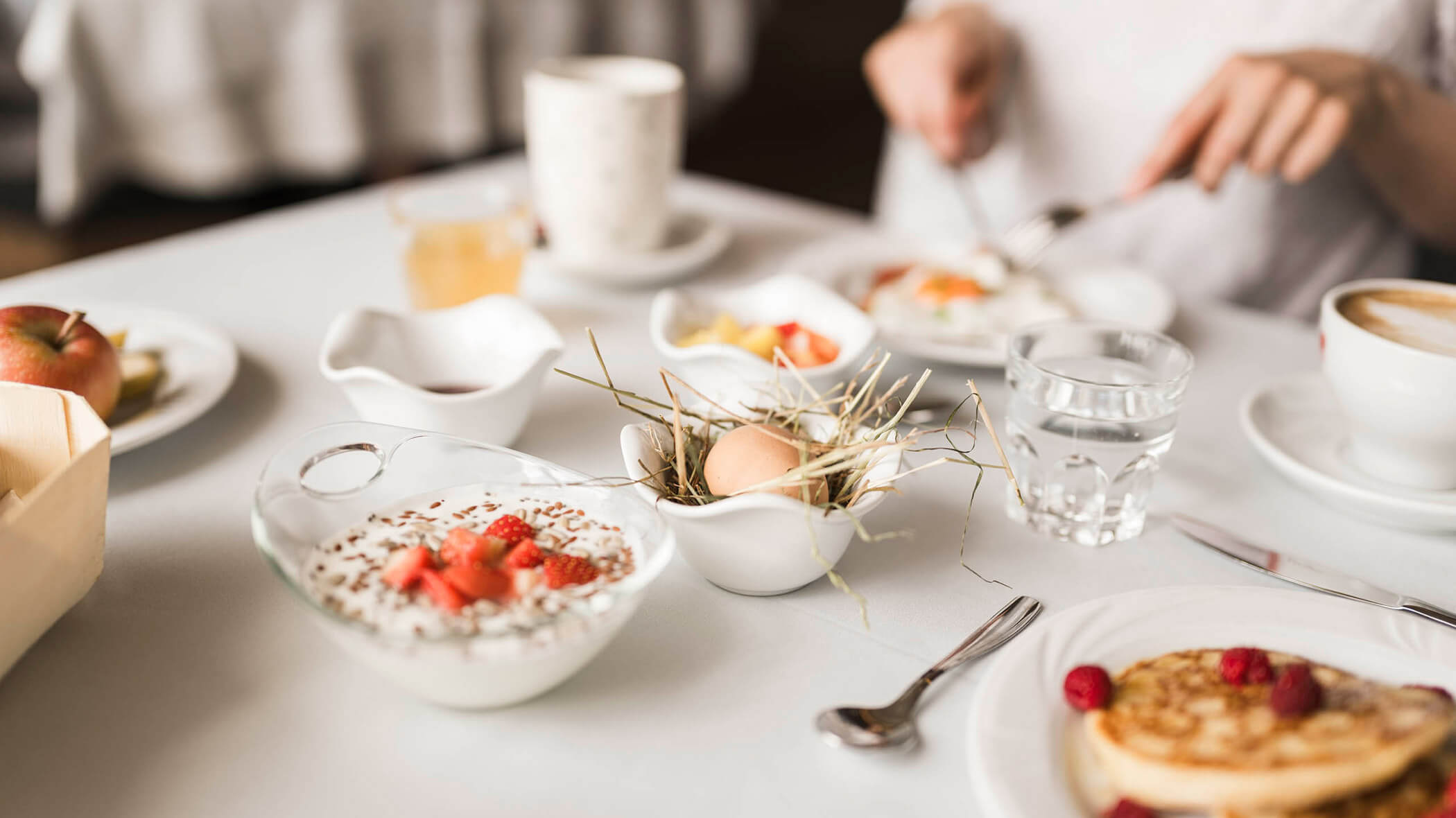 Tavolo della colazione con yogurt, uova, pancake e molto altro