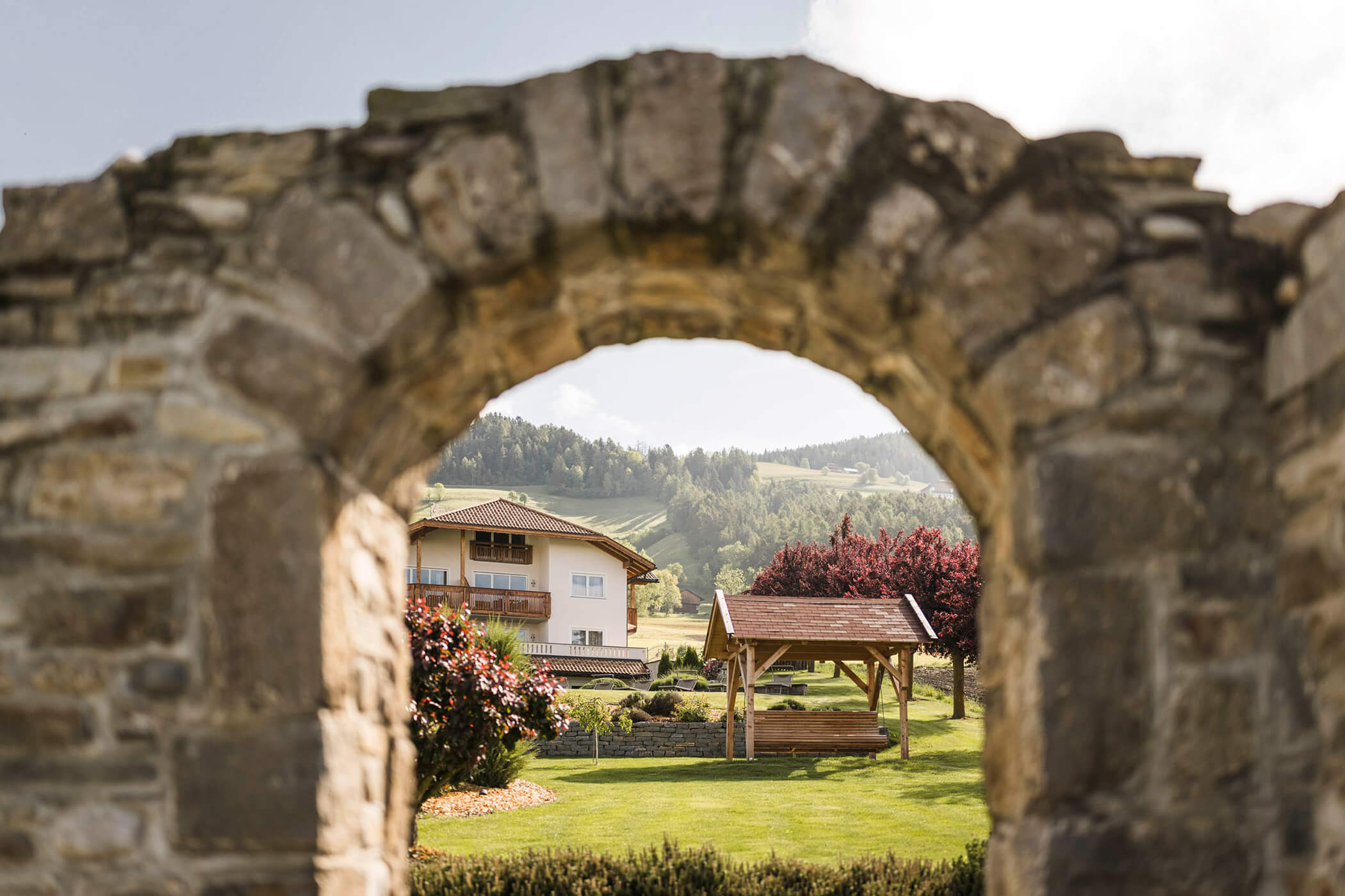 Vista attraverso un cancello in pietra su un prato