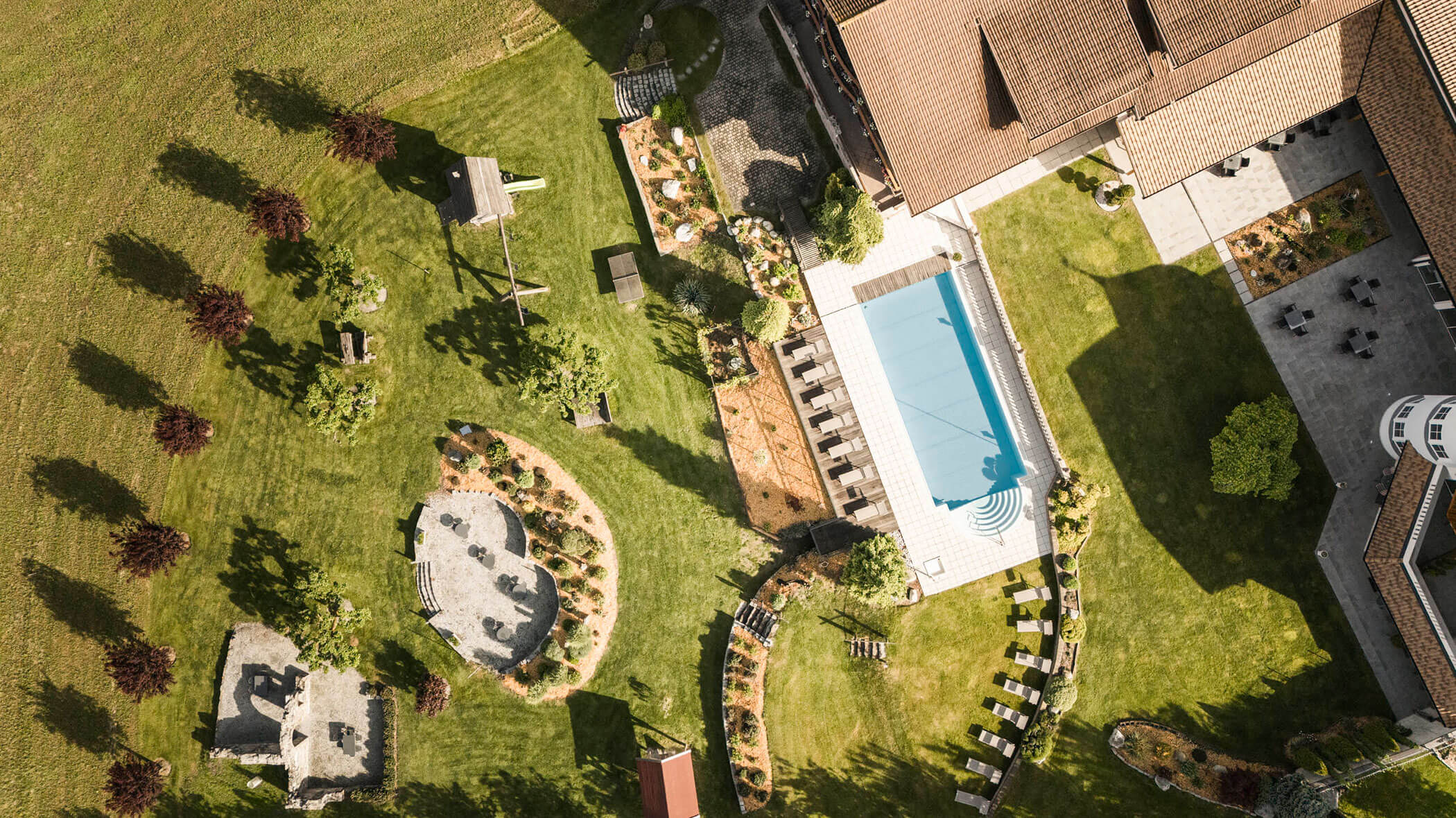 Vogelperspektive auf die Wiese und Liegefläche rund um das Hotel