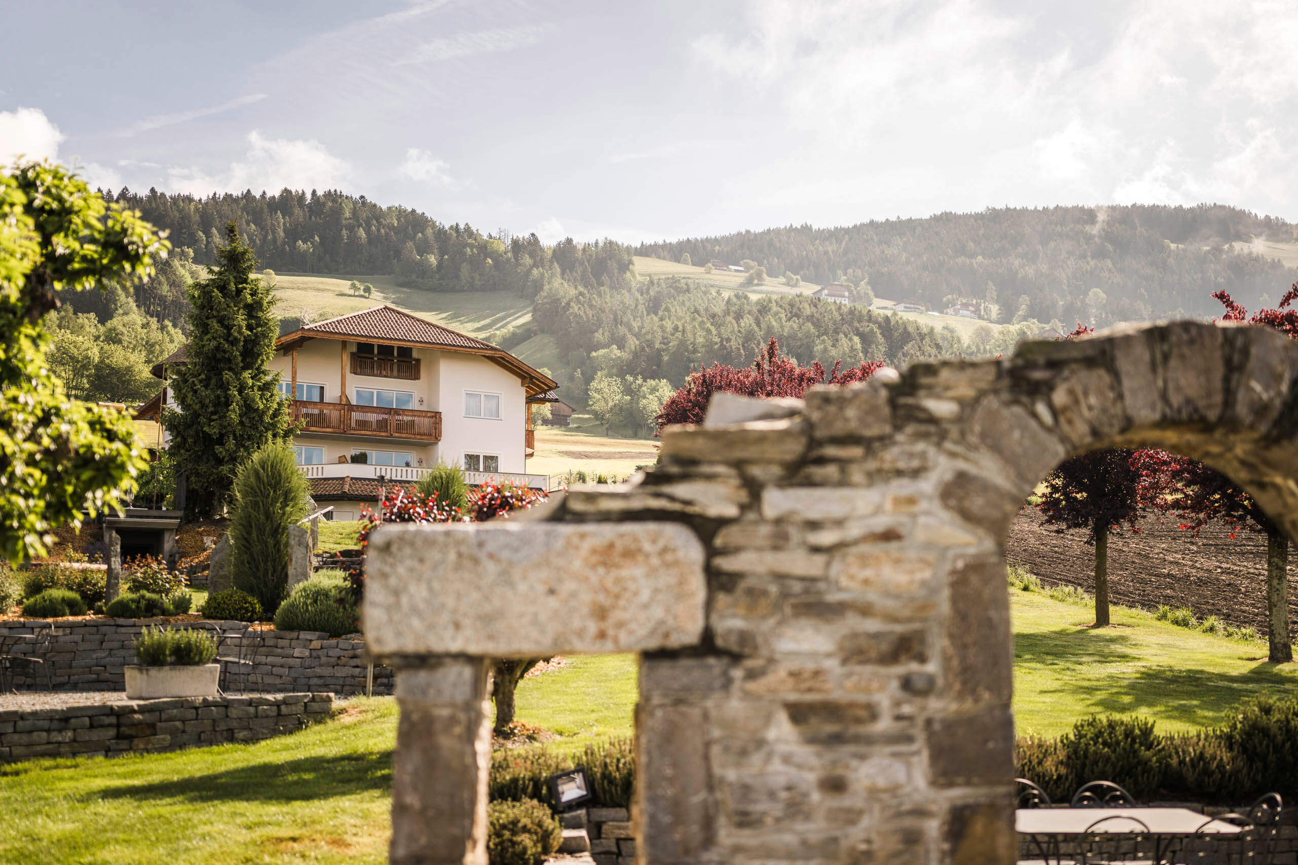 Vista attraverso un cancello in pietra su un prato e l'hotel